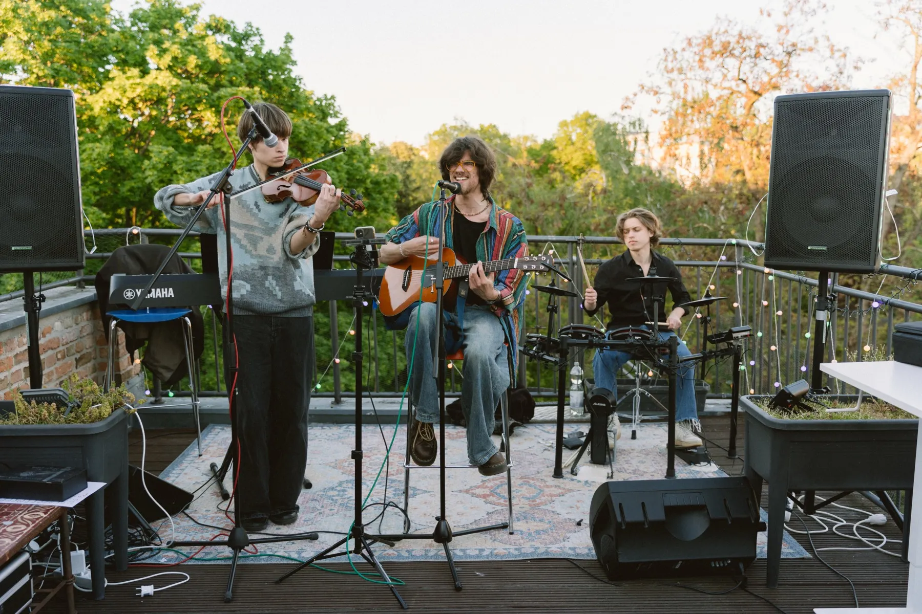 Musicians play violin, guitar, and percussion on a terrace in Berlin.