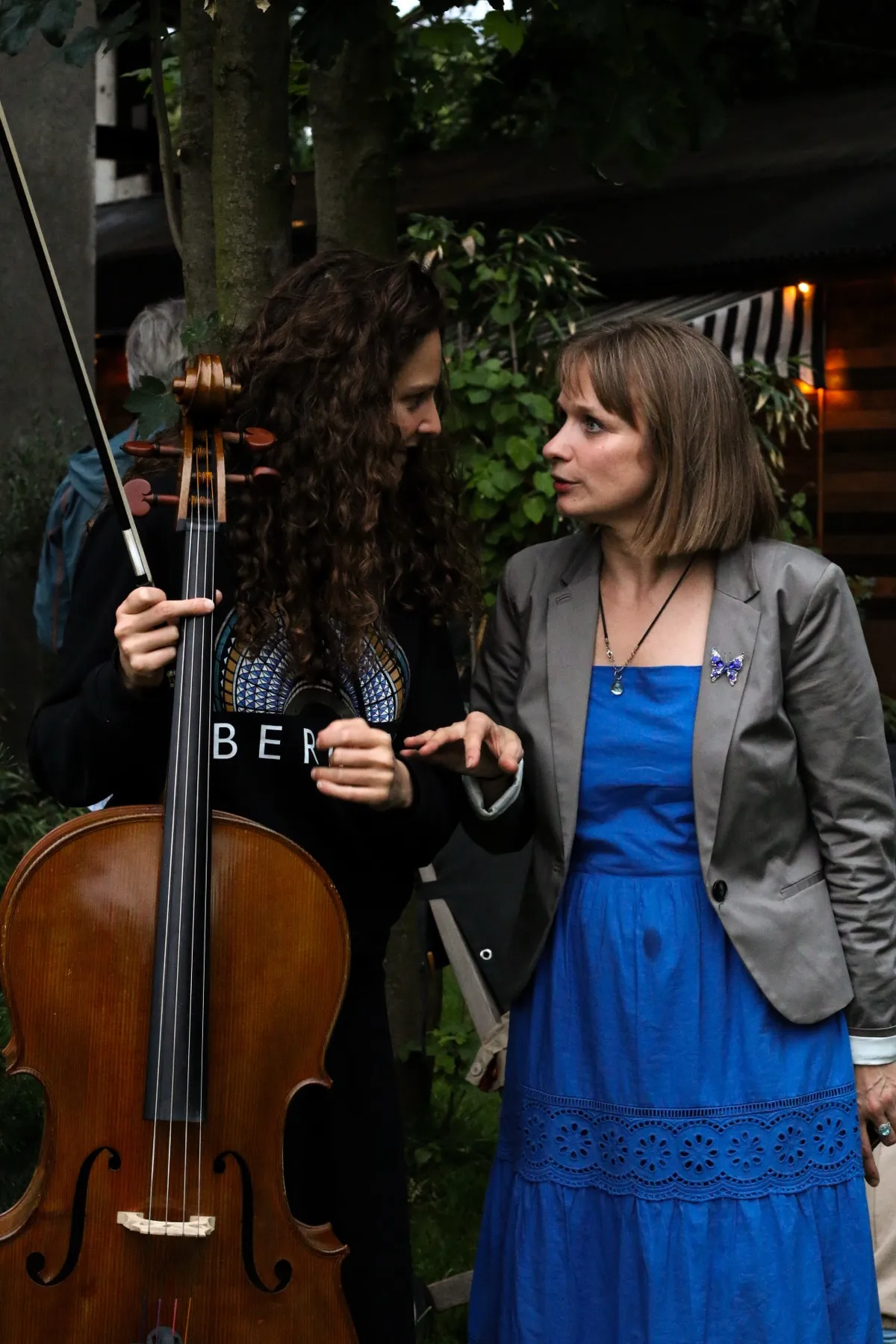 Two musicians talk beside a cello before the charity concert.